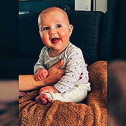 Gabriel a rejoint le concours — aidez-le/la à gagner de superbes lots ! baby, child, smiling, happy, sitting, blanket, hand, indoor, furniture, sofa, clothing, person, portrait, cute, infant, cozy, warm, home, skin, face