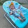 baby, smiling, baby_rocker, outdoor, concrete, grass, colorful, seat, infant, happy, clothing, sock, playful, pattern, child, person, young, cute, strap, blue