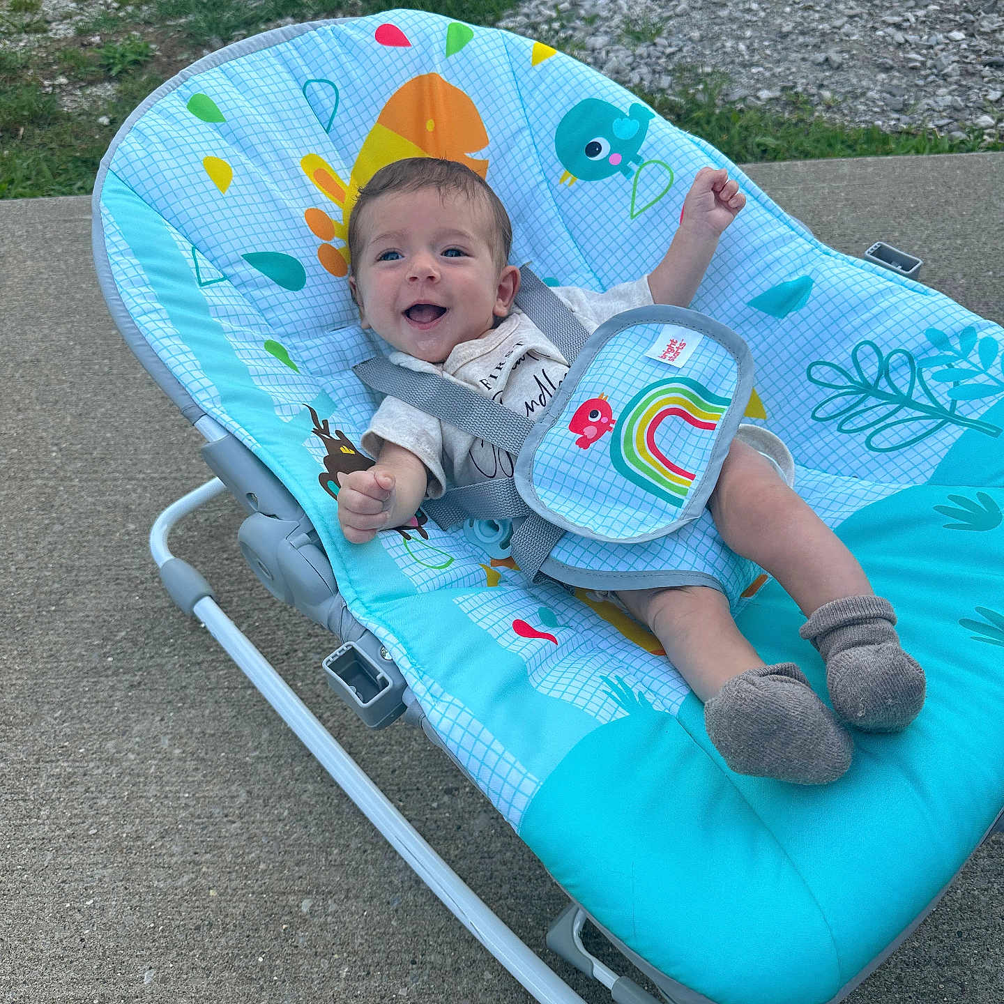 Keeton joined the competition — help win amazing prizes! baby, baby_rocker, blue, child, clothing, colorful, concrete, cute, grass, happy, infant, outdoor, pattern, person, playful, seat, smiling, sock, strap, young