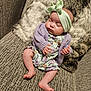 baby, sleeping, infant, headband, bow, purple_cardigan, floral_outfit, couch, furry_pillow, cozy, indoor, person, cute, peaceful, relaxed, small_hands, bare_feet, texture, soft, rest