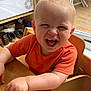 toddler, child, smile, laugh, orange_shirt, wooden_table, high_chair, indoor, washing_machine, shoes, grape, hair, happy, face, person, window, chair, home, daylight, wooden_floor