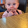 Skylar is registered to the contest to win money with this photo: child, toddler, baby, snack, table, wood, chair, restaurant, indoor, face, hands, food, eating, blue_eyes, curly_hair, clothing, furniture, person, cute, cute_expression