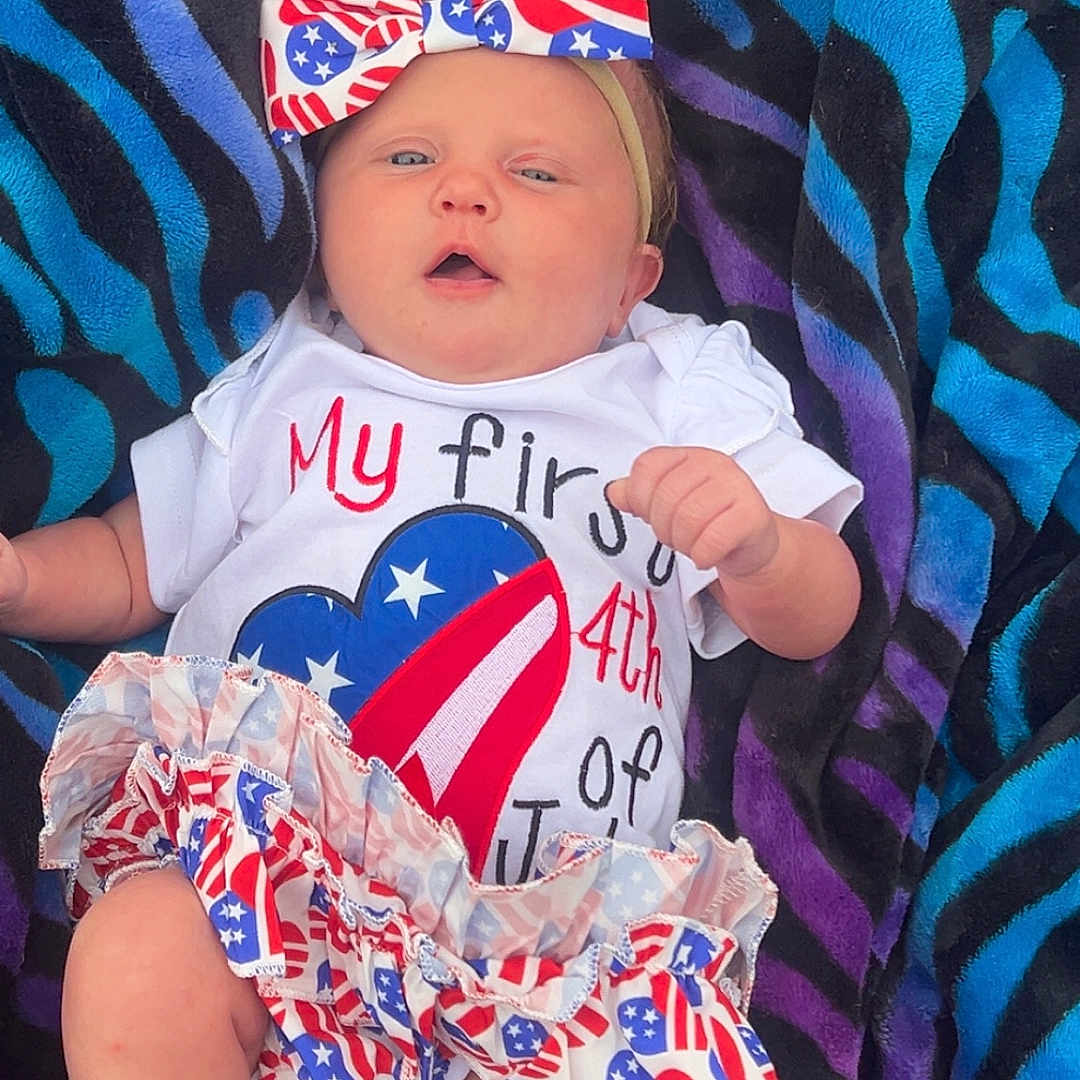 Autumn joined the competition — help win amazing prizes! baby, infant, bow, headband, clothing, blanket, patterned_blanket, face, legs, feet, american_flag, cute, celebration, 4th_of_july, summer, portrait, child, newborn, lying_down, colorful