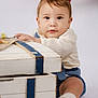 baby, child, toddler, face, clothing, white_background, wooden_chest, blue_stripes, socks, shoes, indoor, portrait, cute, curious, sitting, hand, red_ship_wheel, studio_photo, soft_lighting, young_child