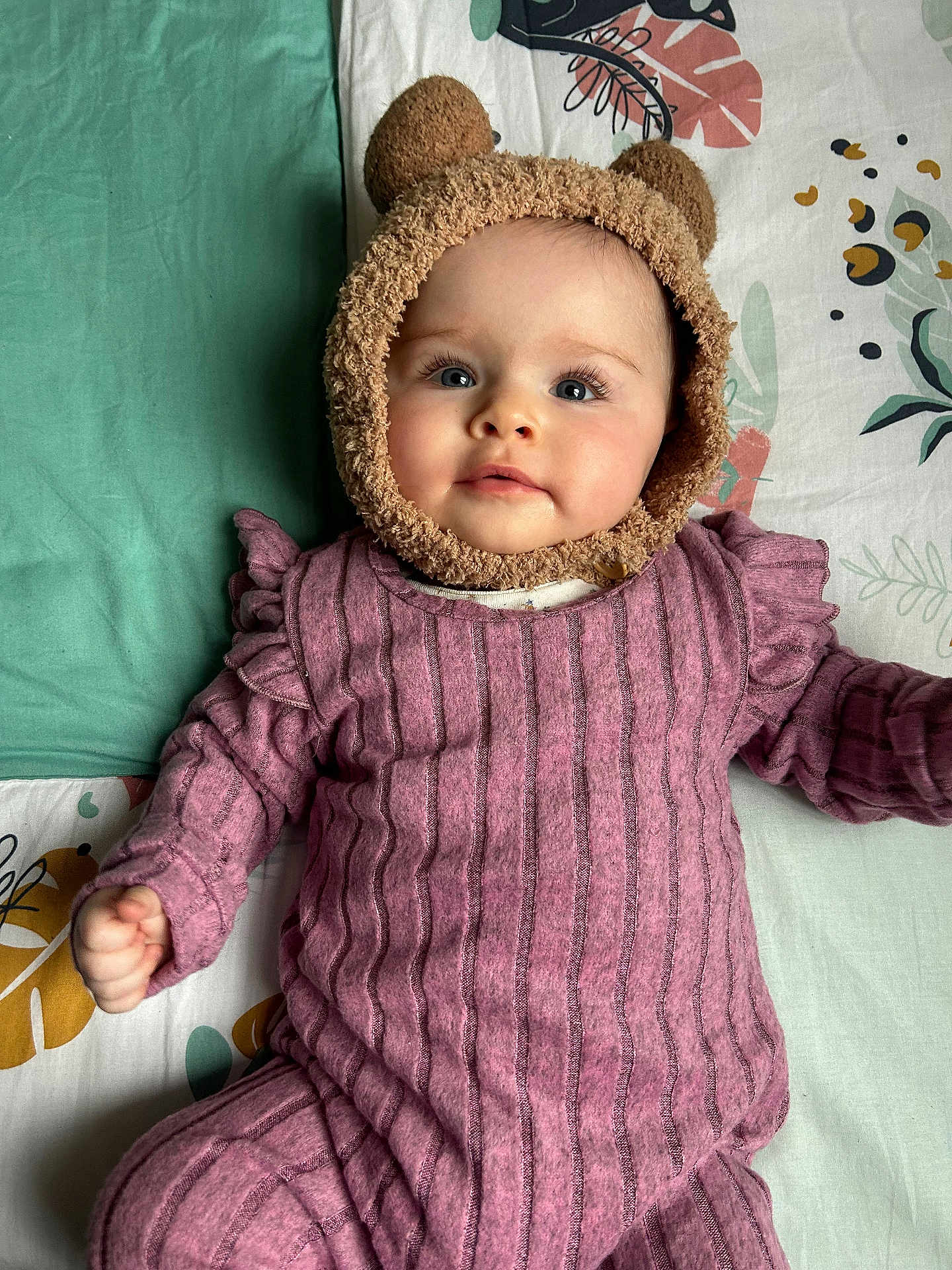 Emy a rejoint le concours — aidez-le/la à gagner de superbes lots ! baby, infant, child, face, hat, bear_ears, purple_clothing, striped_outfit, blanket, patterned_blanket, cute, lying_down, portrait, indoors, soft_texture, young_child, chubby_cheeks, smiling, cozy, warm_clothing