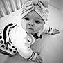 Emy a rejoint le concours — aidez-le/la à gagner de superbes lots ! baby, black_and_white, bow, child, closeup, cozy, crawling, curious, cute, expression, face, hands, headband, indoors, infant, knitted_sweater, person, portrait, soft_surface, young_child