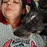 Midnight is registered to the contest to win money with this photo: person, dog, face, cozy, selfie, sweater, cartoon_character, plush_toy, lying_down, resting, indoors, cute, casual, closeup, pet, animal, comfort, relaxed, home, portrait