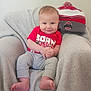 baby, child, infant, smiling, red_shirt, grey_pants, beanie, hat, blanket, chair, indoors, cute, happy, portrait, sitting, feet, hands, face, cozy, soft