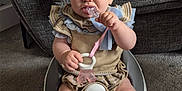Miley is registered to the contest to win money with this photo: baby, baby_seat, carpet, child, clothing, couch, cute, floor, furniture, home, indoor, infant, knees, person, ruffles, serious_expression, sitting, socks, teething_toy, toy