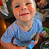 child, smiling, indoor, toy, blue_shirt, floor, wooden_floor, young_child, happy, person, face, play, holding, bottle, clothing, home, colorful, casual, looking_up, cute