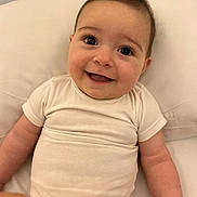 Anastacia a rejoint le concours — aidez-le/la à gagner de superbes lots ! baby, smiling, infant, white_onesie, happy, face, child, cute, portrait, skin, lying_down, indoor, soft, human, young_child, expression, head, eyes, mouth, arm