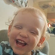 Hudson joined the competition — help win amazing prizes! child, toddler, smiling, indoor, striped_clothing, face, hair, happy, seated, kitchen, cup, sign, furniture, wall, light, person, young_child, casual, expression, portrait