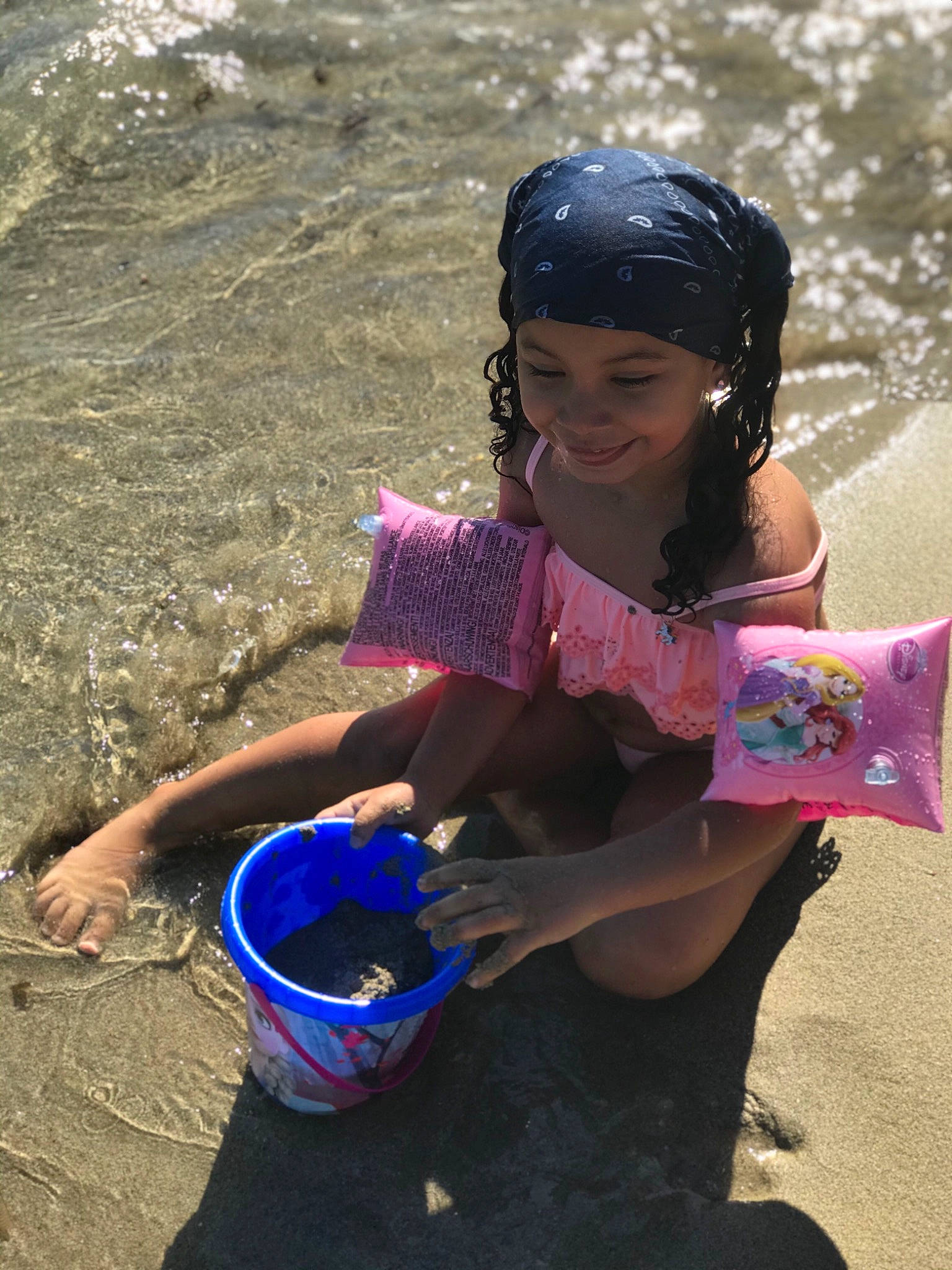 Ilyanna participe au concours pour gagner de l'argent avec cette photo : baby_toddler_clothing, bucket, foot, fun, hair_accessory, hand, headwear, joy, person, pink, play, sand, slipper, summer