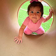 Nayeli is registered to the contest to win money with this photo: baby, bow, child, crawling, curious, cute, daylight, face, fun, grass, hand, outdoor, person, pink_clothing, play, playground, smiling, toddler, tunnel, young