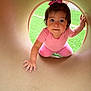 baby, bow, child, crawling, curious, cute, daylight, face, fun, grass, hand, outdoor, person, pink_clothing, play, playground, smiling, toddler, tunnel, young