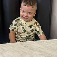 Riann is registered to the contest to win money with this photo: toddler, child, smiling, dinosaur_shirt, marble_table, black_cushion, short_hair, indoors, cute, portrait, sitting, happy, playful, young_child, person, casual_clothing, background, head, face, eyes