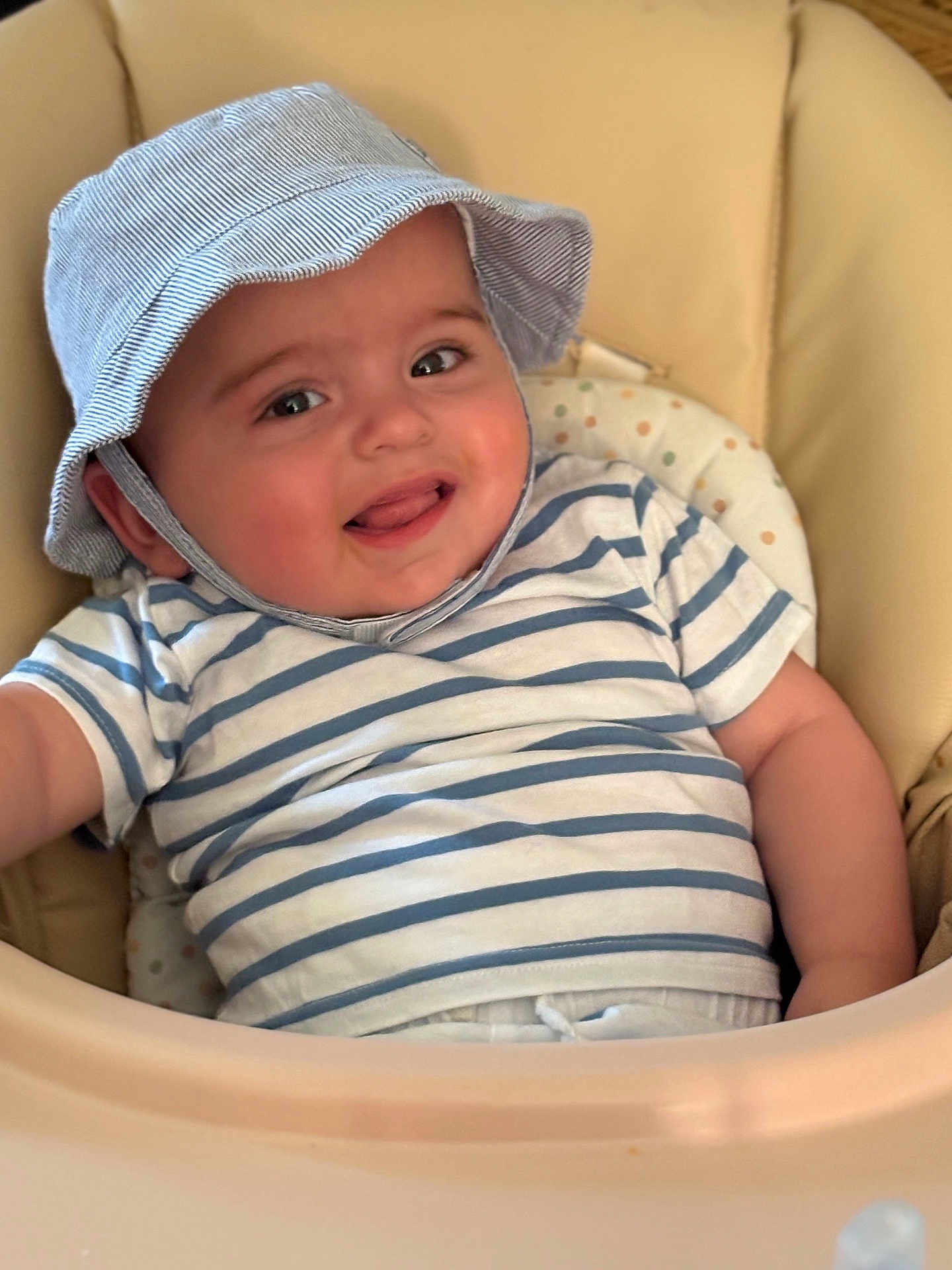 Jonas a rejoint le concours — aidez-le/la à gagner de superbes lots ! baby, child, smiling, hat, striped_shirt, high_chair, indoor, cute, tongue_out, happy, portrait, infant, clothing, face, person, seat, seat_cushion, skin, headwear, baby_furniture