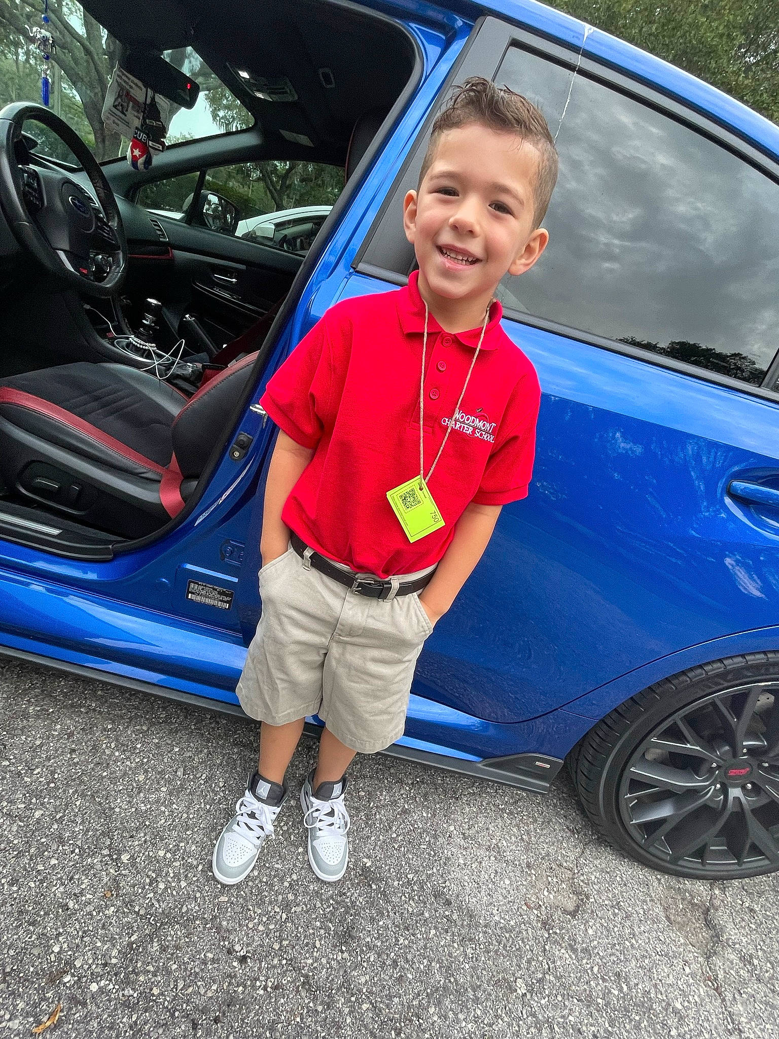 Samuel is registered to the contest to win money with this photo: alloy_wheel, automotive_design, automotive_exterior, automotive_lighting, automotive_tire, blue, bumper, car, fender, hood, joy, motor_vehicle, person, personal_luxury_car, rim, shorts, smile, tire, vehicle, vehicle_door