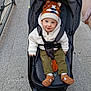 Alexandre a rejoint le concours — aidez-le/la à gagner de superbes lots ! toddler, stroller, child, hat, knitwear, sweater, shoes, urban, pavement, outdoor, baby, seatbelt, curious, smile, face, person, winter_clothing, cute, warm, casual