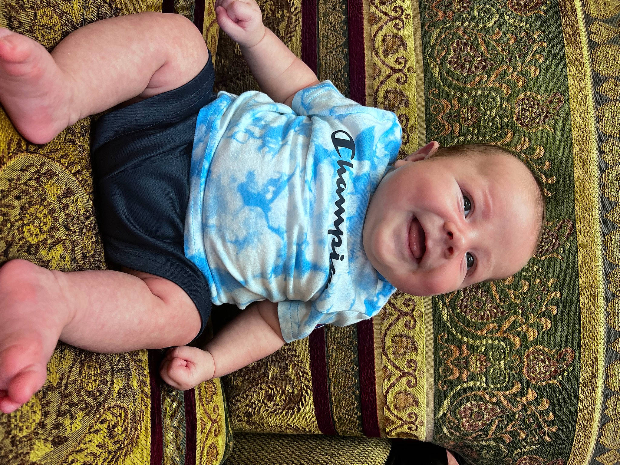 Kooper is registered to the contest to win money with this photo: baby, baby_toddler_clothing, cheek, comfort, eye, finger, fun, grass, hand, head, human_body, leaf, leg, mouth, pattern, person, skin, smile, toddler, tree