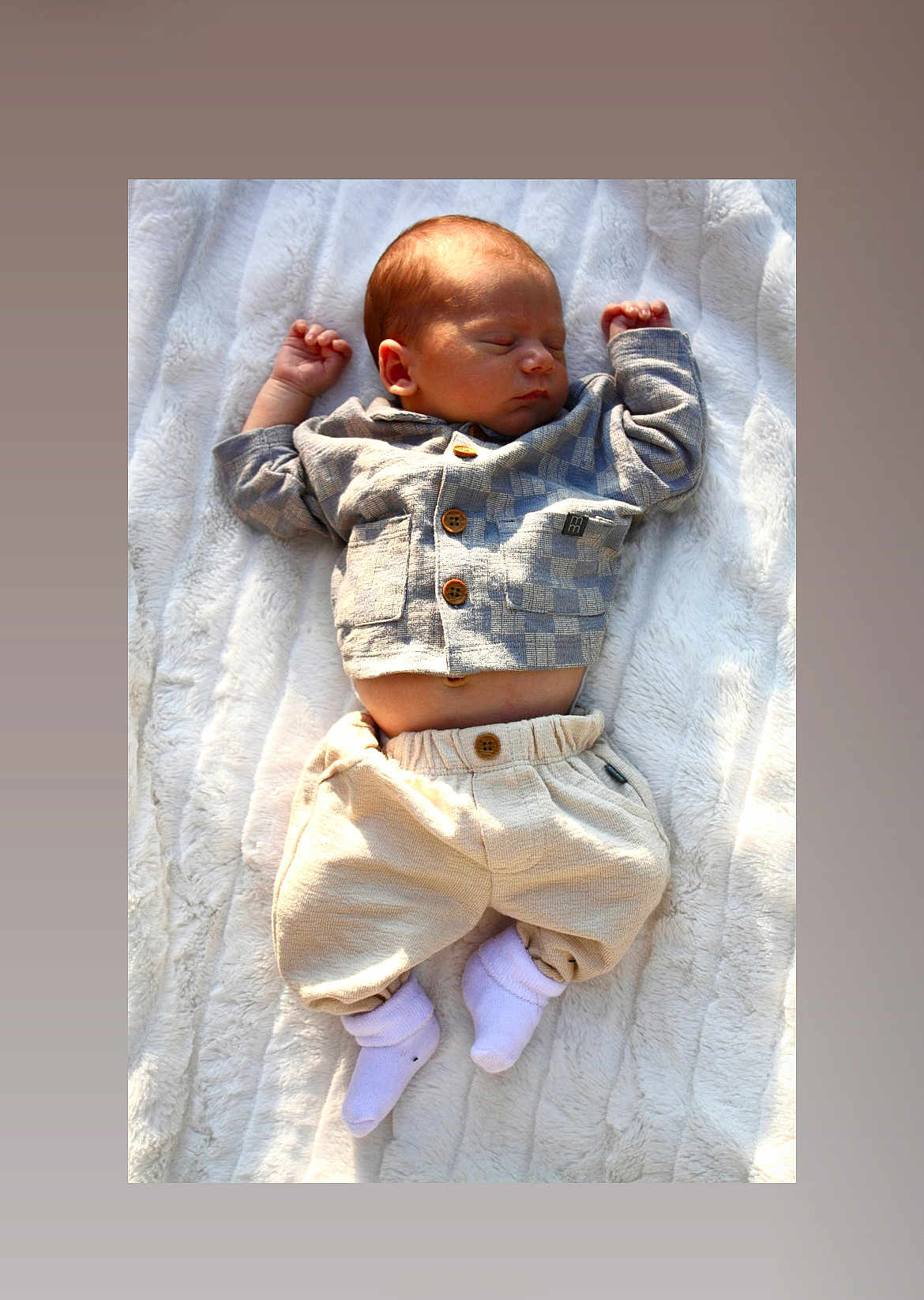 Hamza is registered to the contest to win money with this photo: baby, sleeping, infant, blanket, soft_texture, clothing, neutral_colors, cozy, peaceful, newborn, portrait, lying_down, hand, footwear, white_socks, natural_light, indoors, cute, small, relaxed