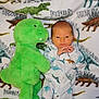 baby, dinosaur, plush_toy, blanket, pajamas, infant, cute, soft_toy, child, sleepwear, pattern, animal_print, lying_down, indoors, young_child, cozy, resting, small_baby, nursery, comfort