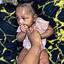 Fatoumata Binta a rejoint le concours — aidez-le/la à gagner de superbes lots ! baby, infant, hand, finger, chewing, cute, child, person, blanket, pattern, black, yellow, clothing, pink, puffs, hair, skin, lying, comfort, closeup