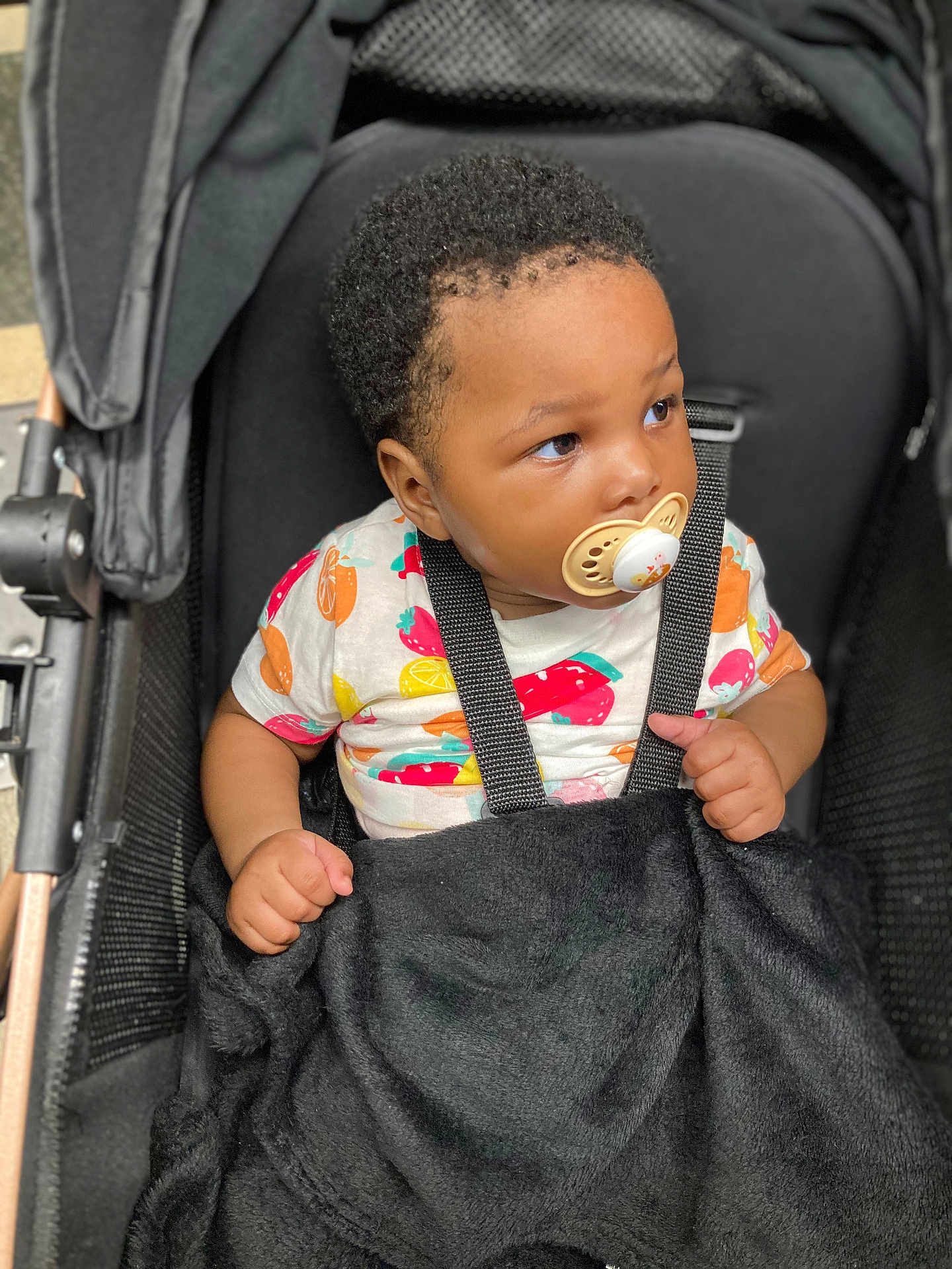 Fatoumata Binta a rejoint le concours — aidez-le/la à gagner de superbes lots ! toddler, child, pacifier, stroller, blanket, colorful_clothing, curly_hair, straps, seated, indoor, looking_away, baby, cute, infant, black_blanket, safety_harness, young_child, portrait, casual, resting