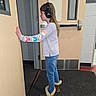 child, headphones, boots, jeans, long_hair, door, school, hallway, carpet, wall, window, casual_clothing, indoor, side_view, person, young, listening, curious, standing, footwear