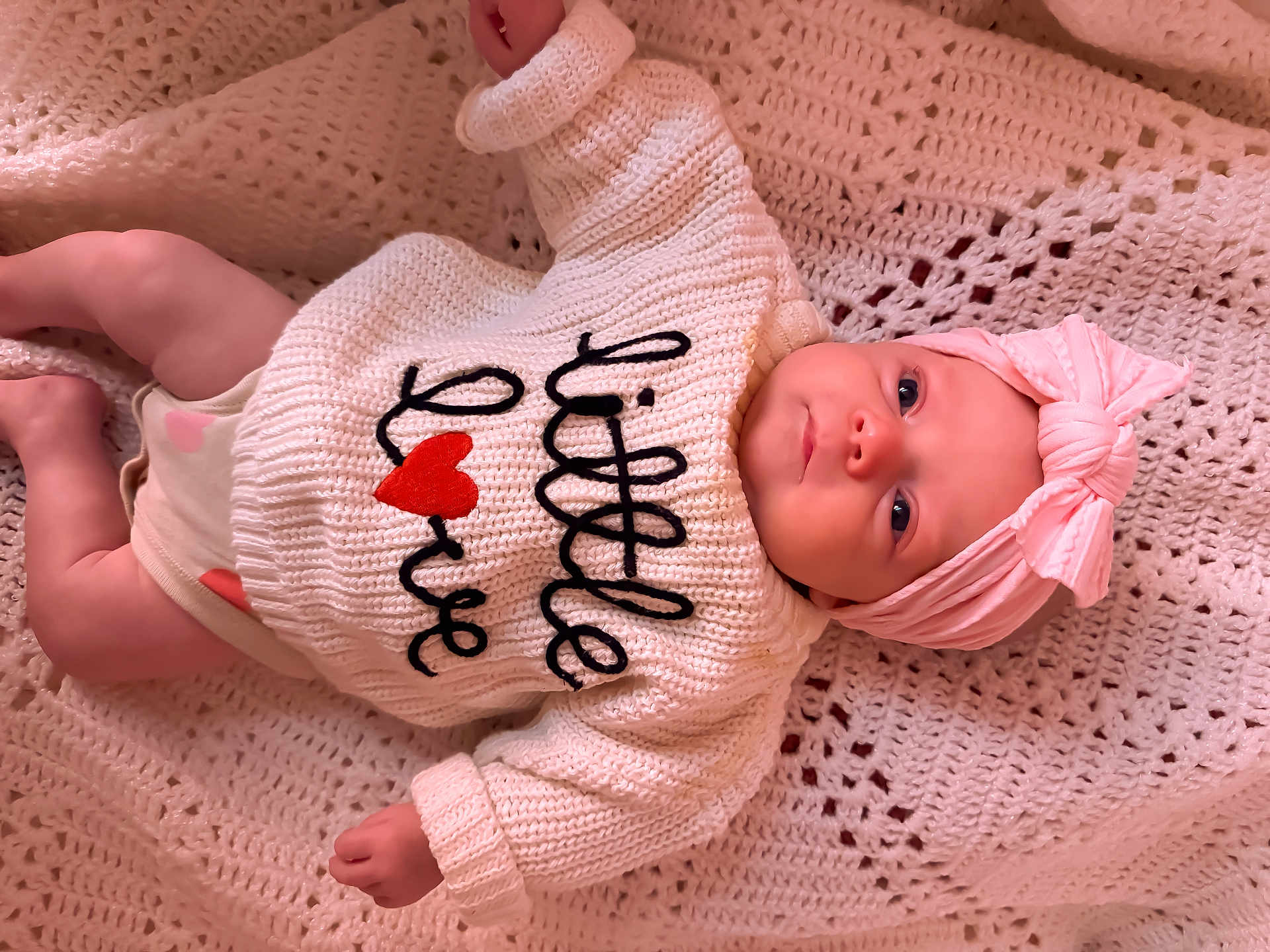 Jolene is registered to the contest to win money with this photo: baby, infant, newborn, pink_headband, knitted_blanket, sweater, heart, eyes, smile, portrait, lying_down, cozy, crochet, soft_texture, adorable, cute, one_person, close_up, skin, clothing