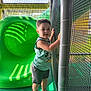 Banks is registered to the contest to win money with this photo: child, toddler, playground, slide, green_slide, netting, safety_net, outdoor_play, sunlight, shadow_pattern, casual_clothing, sneakers, shorts, tank_top, mickey_mouse, happy, smiling, play_area, daylight, fun