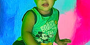 Banks is registered to the contest to win money with this photo: child, boy, green_shirt, mickey_mouse, shorts, colorful_background, abstract_art, blue, pink, red, casual_pose, smiling, portrait, indoor, young, person, artistic, vibrant, playful, relaxed