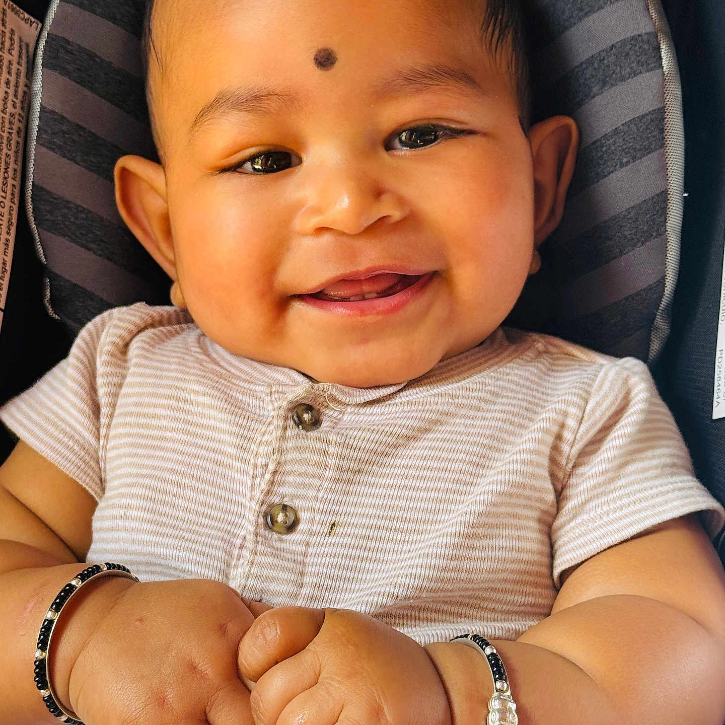 Mayank joined the competition — help win amazing prizes! baby, infant, child, smiling, portrait, close_up, car_seat, seated, striped, clothing, bracelets, hands, face, eyes, hair, gummy_smile, indoor, happy, adorable, photography