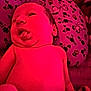 baby, newborn, infant, tongue_out, pink_light, pillow, pattern, cartoon_characters, flower_pattern, skin, face, head, lying_down, closeup, cute, expression, child, indoors, soft_light, person