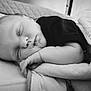 baby, infant, newborn, sleeping, blanket, pillow, bed, face, hand, arm, monochrome, black_and_white, portrait, close_up, peaceful, curled_up, soft_texture, clothing, nursery, resting