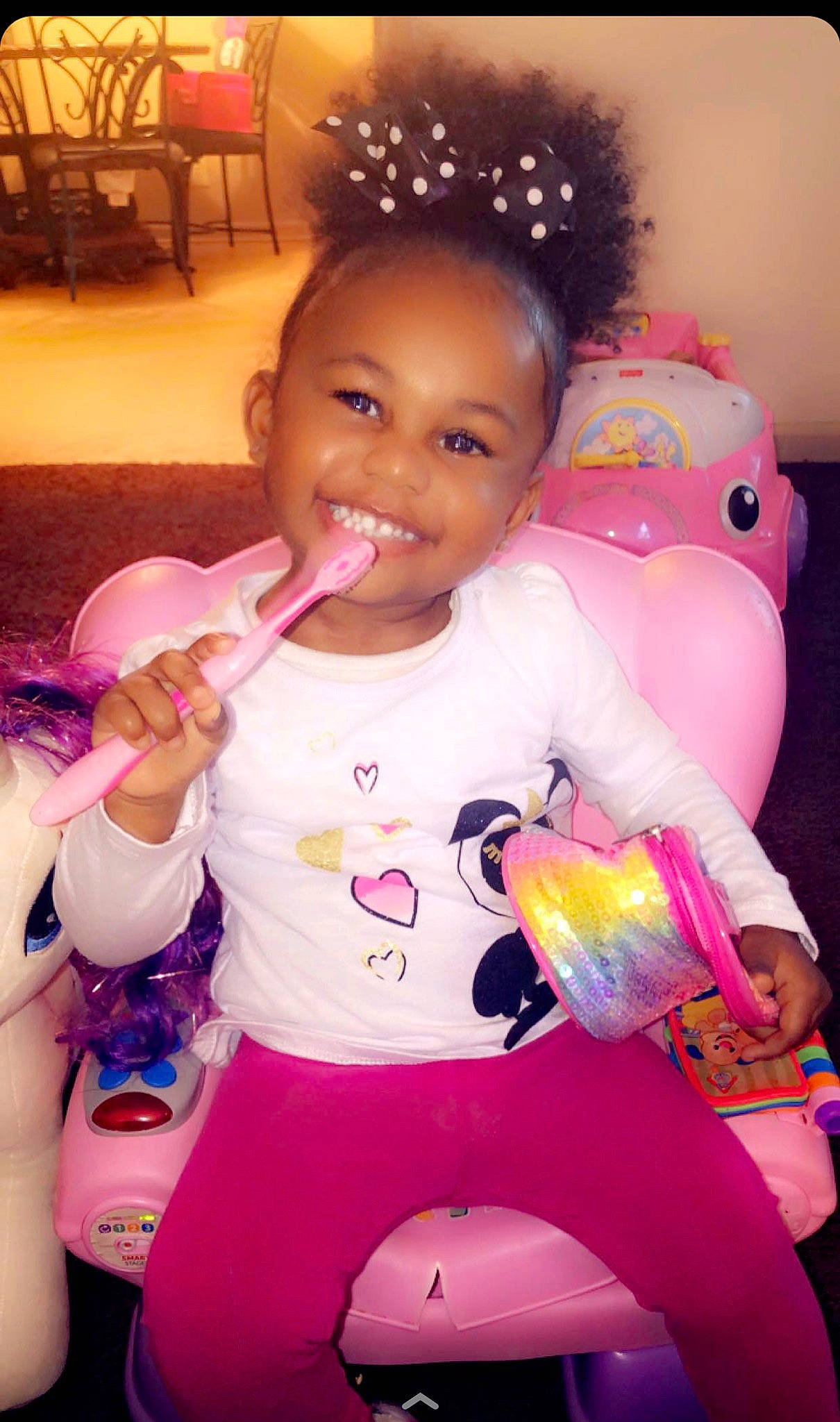 Cori is registered to the contest to win money with this photo: baby_toddler_clothing, chair, cheek, child, eyelash, face, facial_expression, finger, fun, gesture, happy, head, joy, organ, person, pink, skin, smile, snapshot, thumb