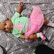 Imogen is registered to the contest to win money with this photo: baby, child, tutu, headband, socks, shirt, patterned_bedspread, pink, green, flower, lying_down, cute, infant, portrait, indoors, clothing, bed, soft_toys, accessory, footwear
