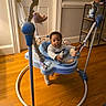 baby, infant, child, activity_jumper, toy, sitting, indoors, wooden_floor, home, playroom, colorful, curious, portrait, face, eyes, clothing, furniture, door, shelf, social_media_screenshot