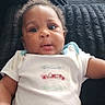 Deandre is registered to the contest to win money with this photo: baby, infant, child, portrait, sitting, lying_down, couch, sofa, blanket, onesie, clothing, face, eyes, hair, indoor, home, photograph, vehicle_design, watermark, wide_eyed