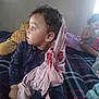 Ezekiel joined the competition — help win amazing prizes! baby, child, toddler, indoor, blanket, toy, plaid, bed, curly_hair, blue_clothing, pink_blanket, playing, window_light, person, face, hand, furniture, sleepwear, candid, soft_light