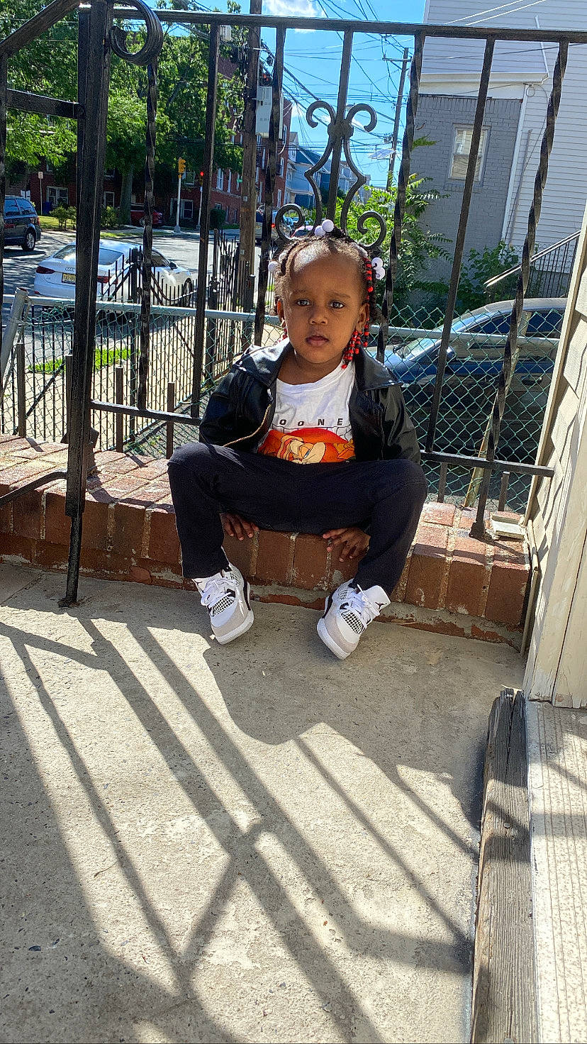 Mikayla joined the competition — help win amazing prizes! boot, car, child, city, fence, flooring, fun, grass, leg, leisure, person, plant, public_space, recreation, road_surface, sidewalk, sitting, sneakers, t_shirt, toddler