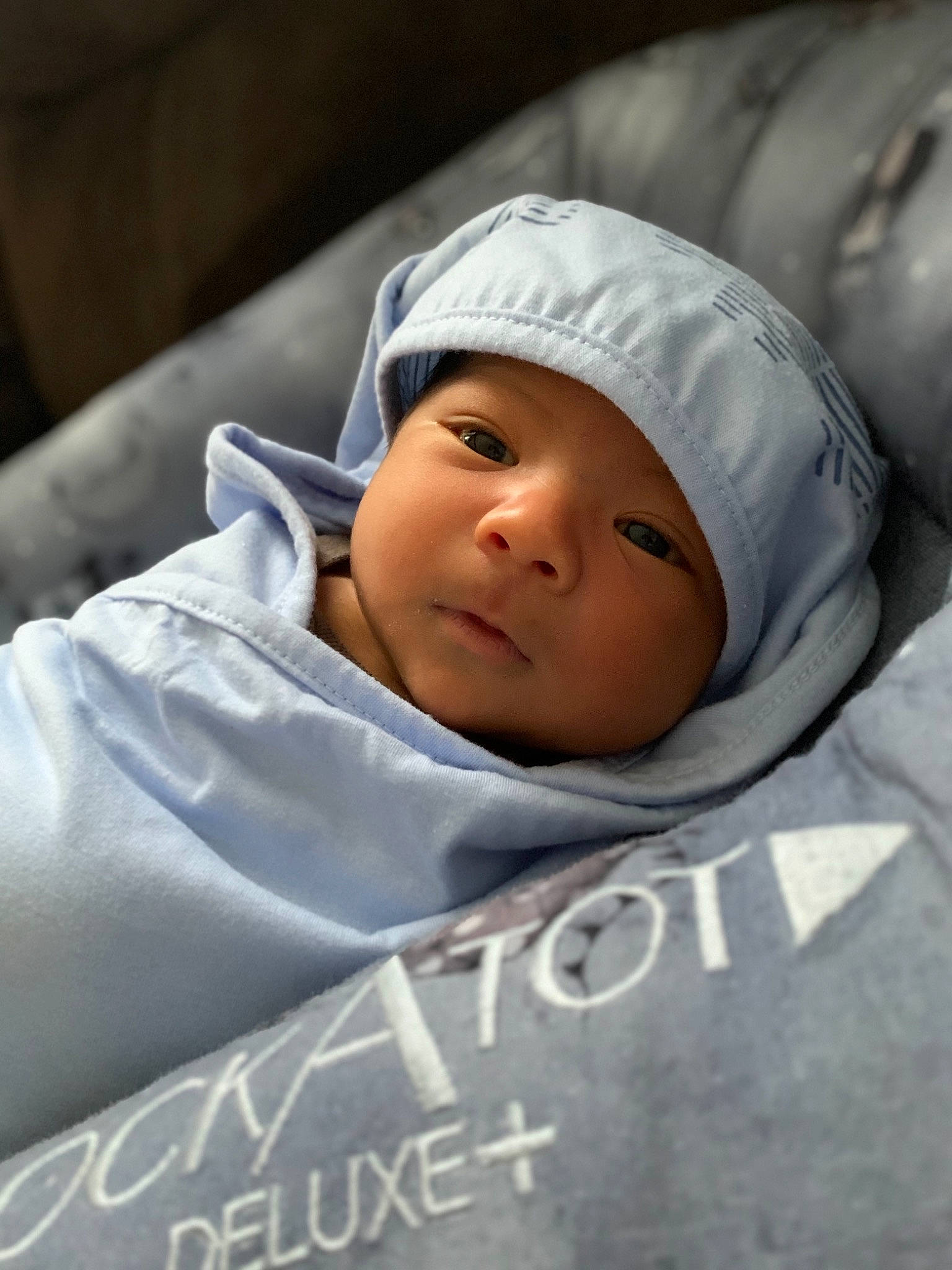 Lionel is registered to the contest to win money with this photo: baby, baby_products, baby_toddler_clothing, cap, cheek, child, chin, comfort, eye, eyebrow, flash_photography, happy, hat, headwear, linens, monochrome_photography, person, portrait_photography, room, sitting