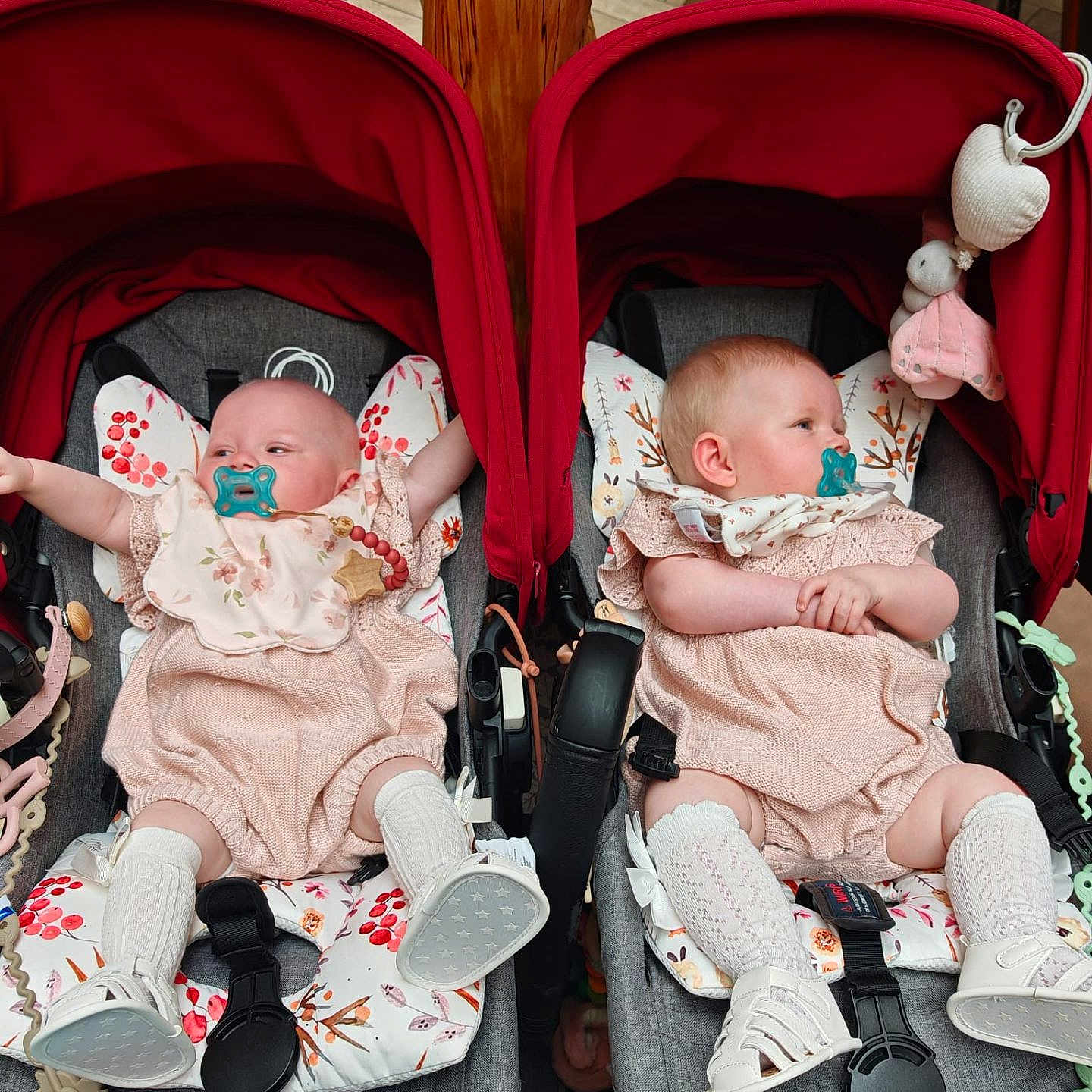 Iylaand Immi joined the competition — help win amazing prizes! baby, child, cushion, cute, indoor, infant, matching_outfits, pacifier, person, pink, playful, red_canopy, relaxing, seated, shoes, socks, stroller, toy, white, wooden_floor