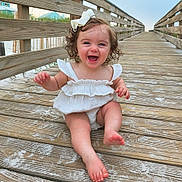 Remi joined the competition — help win amazing prizes! baby, child, girl, smiling, curly_hair, bow, white_dress, barefoot, boardwalk, wooden, outdoor, sand, happy, summer, nature, portrait, cute, playful, vacation, sunset