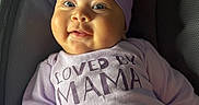 Evangeline joined the competition — help win amazing prizes! baby, infant, smile, face, headwear, turban, clothing, purple, shirt, text, love, happy, cheeks, person, seated, indoor, portrait, closeup, child, couch