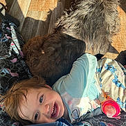 Lyric is registered to the contest to win money with this photo: toddler, child, dog, smiling, bottle, blanket, floor, sunlight, indoor, happy, cute, pet, fur, pajamas, patterned, cozy, relaxed, playful, home, resting