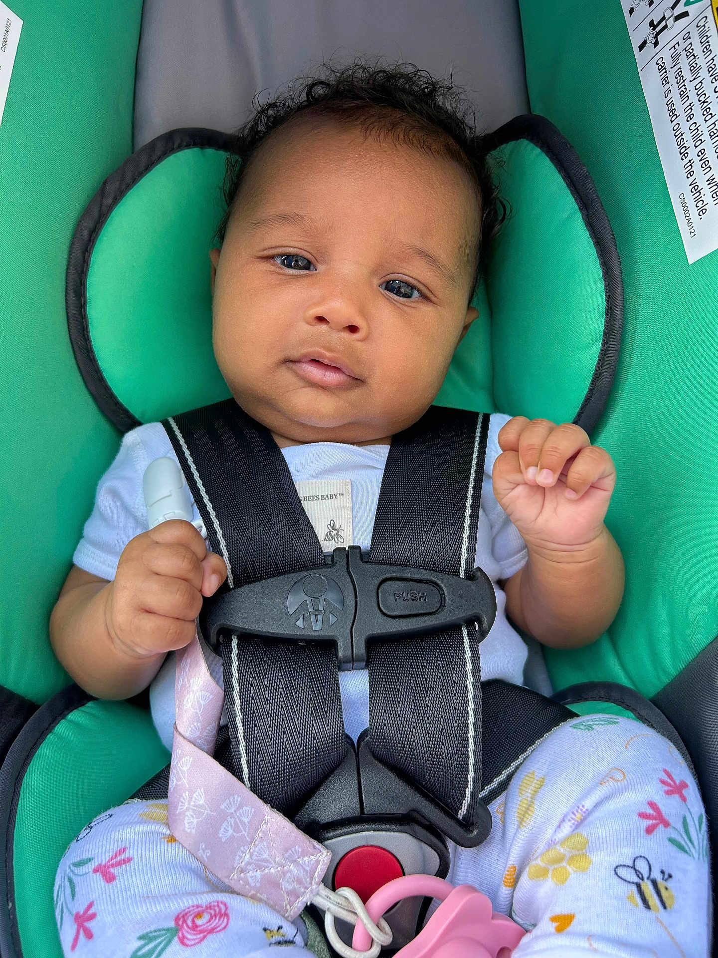 Olivia joined the competition — help win amazing prizes! baby, car_seat, child, infant, straps, pacifier, clothing, floral_pattern, cute, seat_belt, safety, pink, teal, hand, head, portrait, person, young_child, indoors, closeup