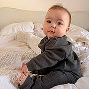 Livio a rejoint le concours — aidez-le/la à gagner de superbes lots ! baby, infant, child, bed, blanket, pajamas, foot, hand, face, expression, indoor, soft_lighting, white, gray_clothing, cute, sitting, pillow, cozy, curious, portrait