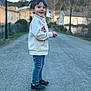child, boy, smiling, standing, road, jeans, jacket, outdoor, mountains, trees, shoes, casual_clothing, daylight, nature, happy, person, scenic, background, side_view, portrait