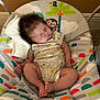 baby, sleeping, infant, baby_seat, patterned_fabric, monkey_design, palm_tree, colorful, cozy, indoor, carpet, white_cloth, cute, child, legs_crossed, onesie, soft_lighting, peaceful, portrait, head_support